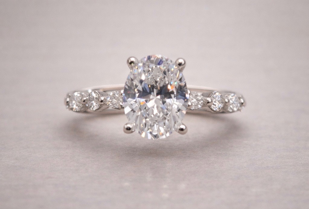 oval diamond set in white gold with marquise and round single prong side stones